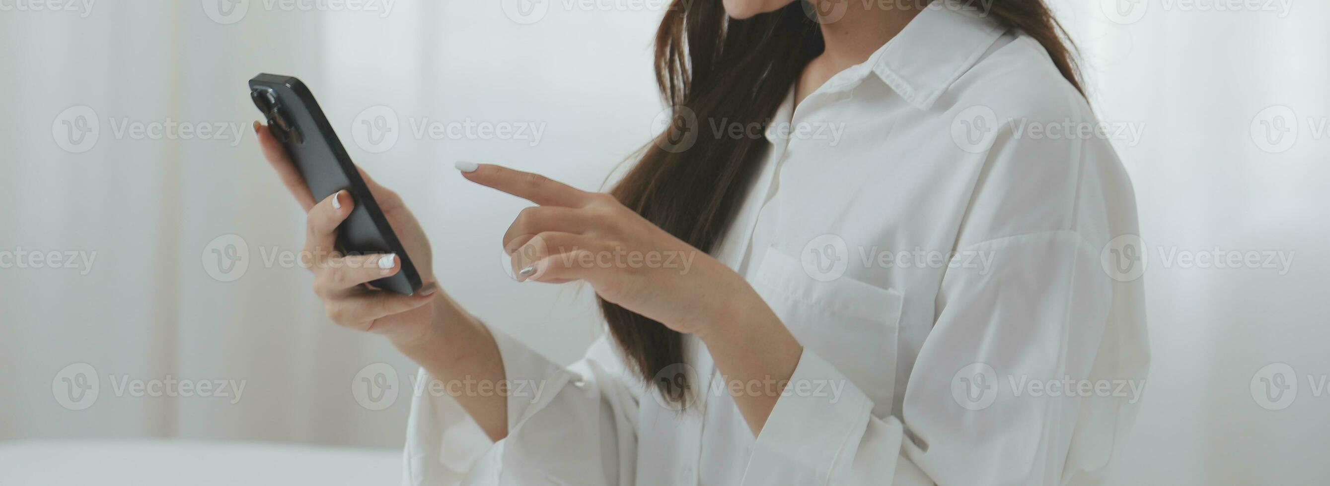 Happy young female in casual clothes smiling and looking at camera while using laptop on bed in bedroom at home photo