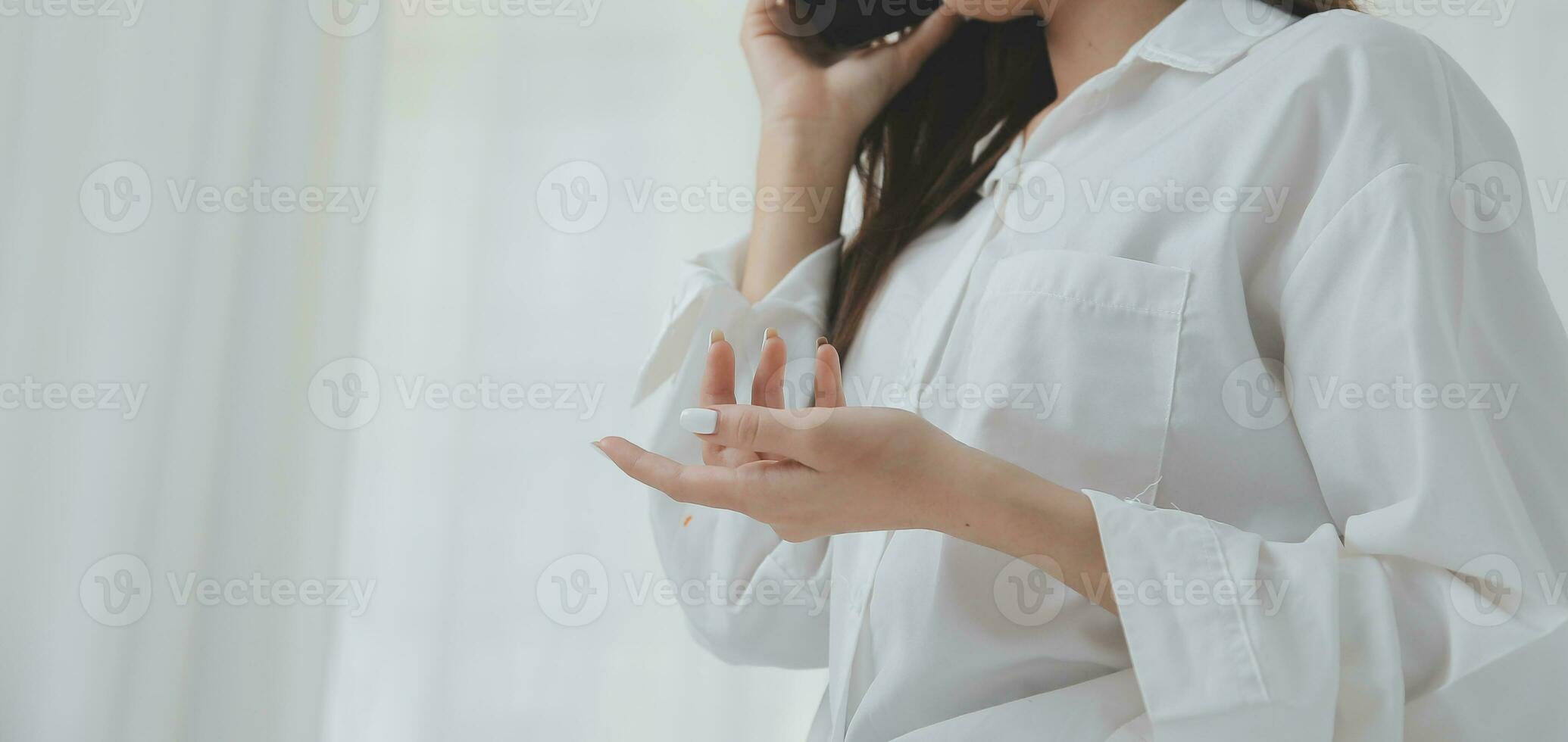 Happy young female in casual clothes smiling and looking at camera while using laptop on bed in bedroom at home photo