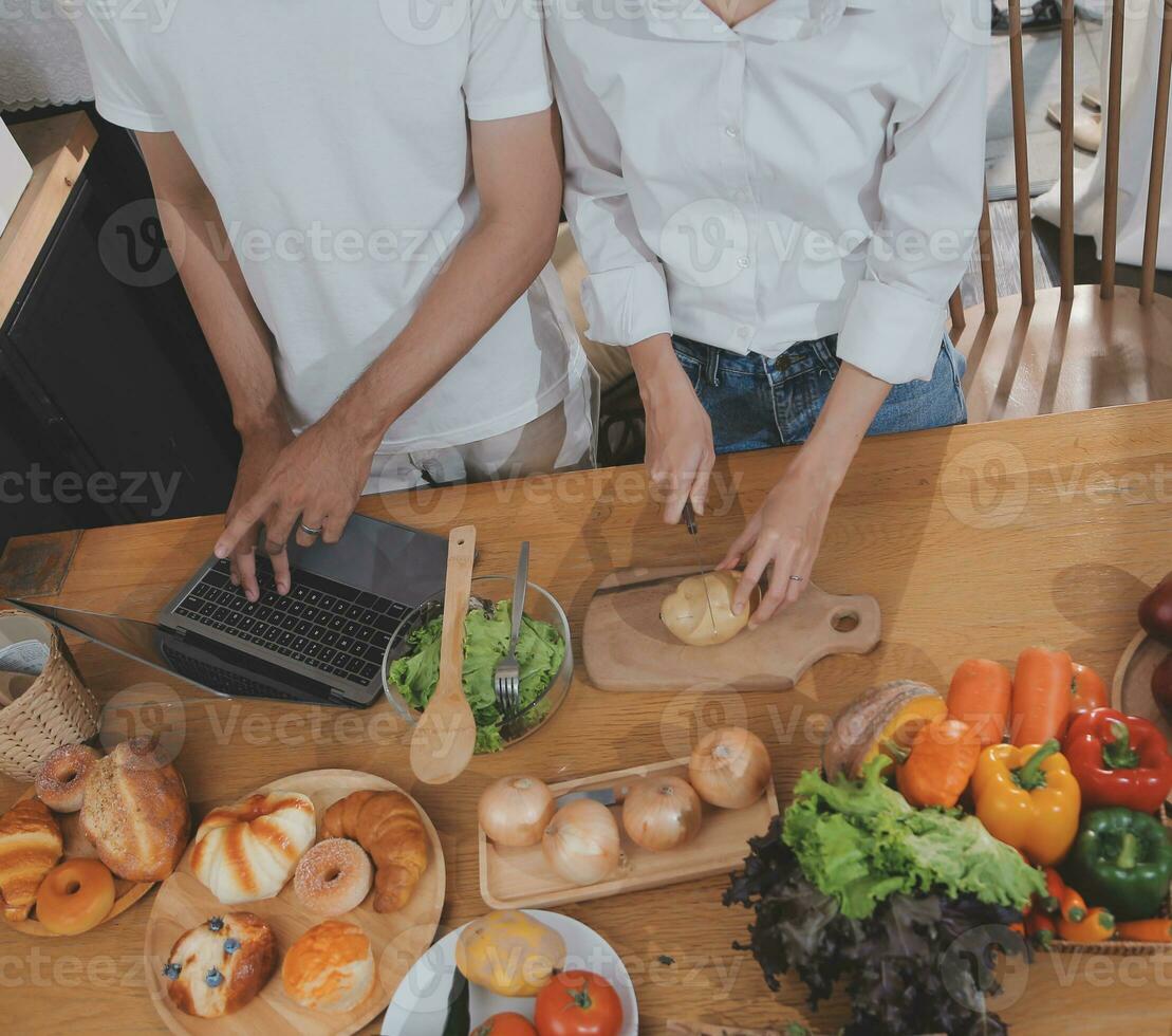 Handsome man sitting near his wife at kitchen. Family couple see social media, surf the web while sitting at kitchen table with generic laptop. Couple working with laptop at home photo