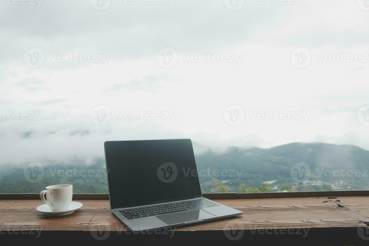 Computer Monitor, Keyboard, coffee cup and Mouse with Blank is on the work table at the sky mountain river and trees front view background. photo