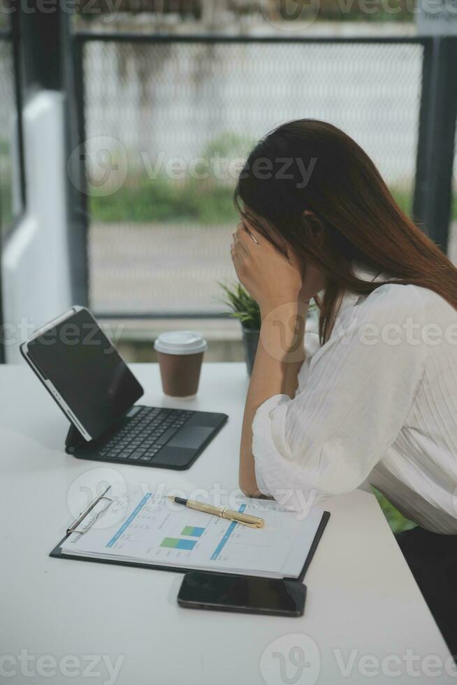 Portrait of Young Asian woman hand freelancer is working her job on computer tablet in modern office. Doing accounting analysis report real estate investment data, Financial and tax systems concept. photo
