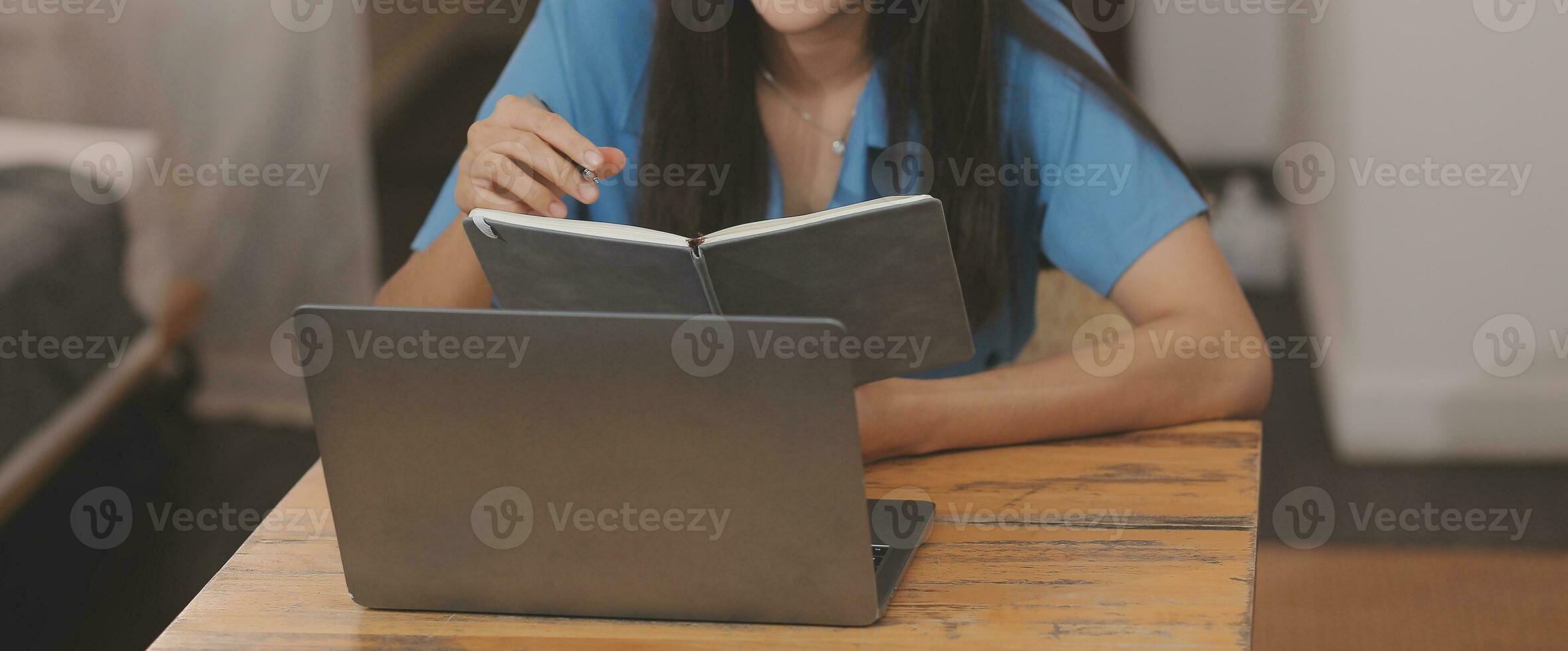 Young Asian woman with beautiful face, long hair, blue shirt lying on bed in white bedroom at home with cup of coffee and video call with laptop talking to relatives on vacation. holiday concept. photo