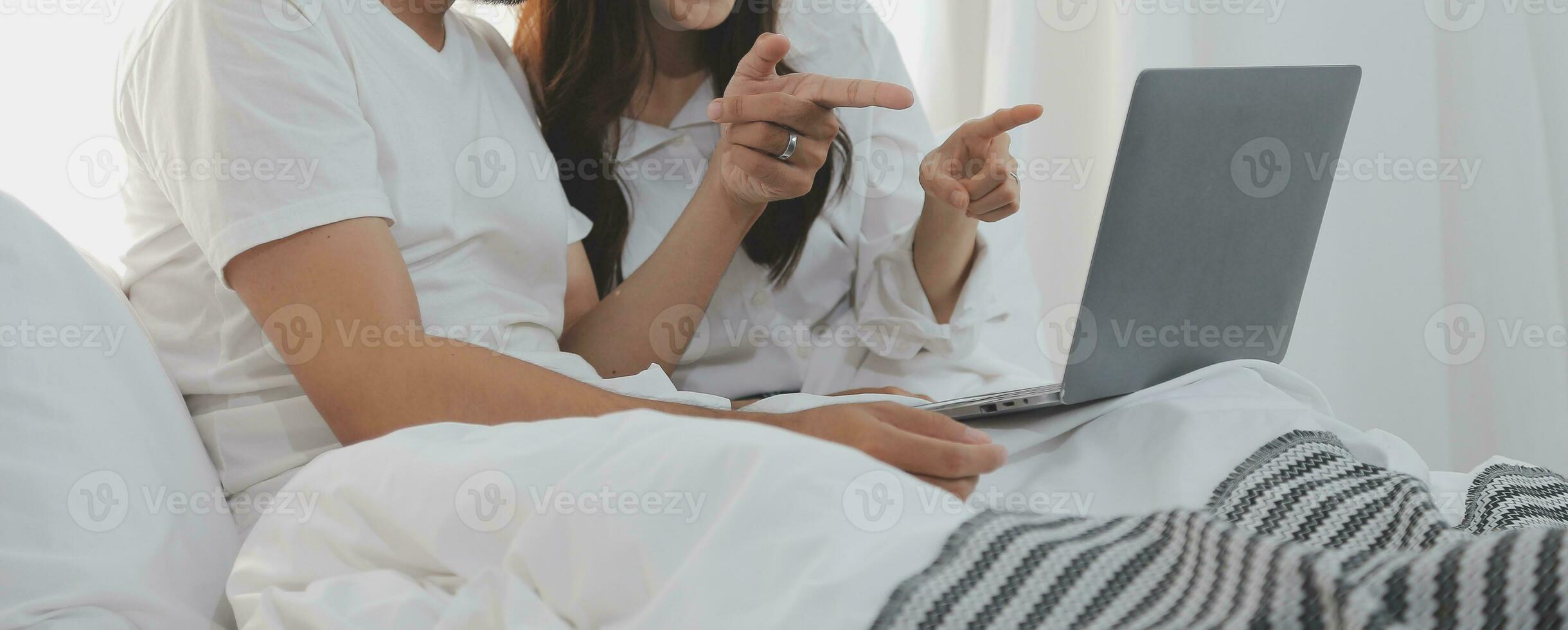 Portrait of young happy couple using laptop at night, using modern technology having fun with glowing screen in dark office or at home, startup business meeting video call distance of young business photo