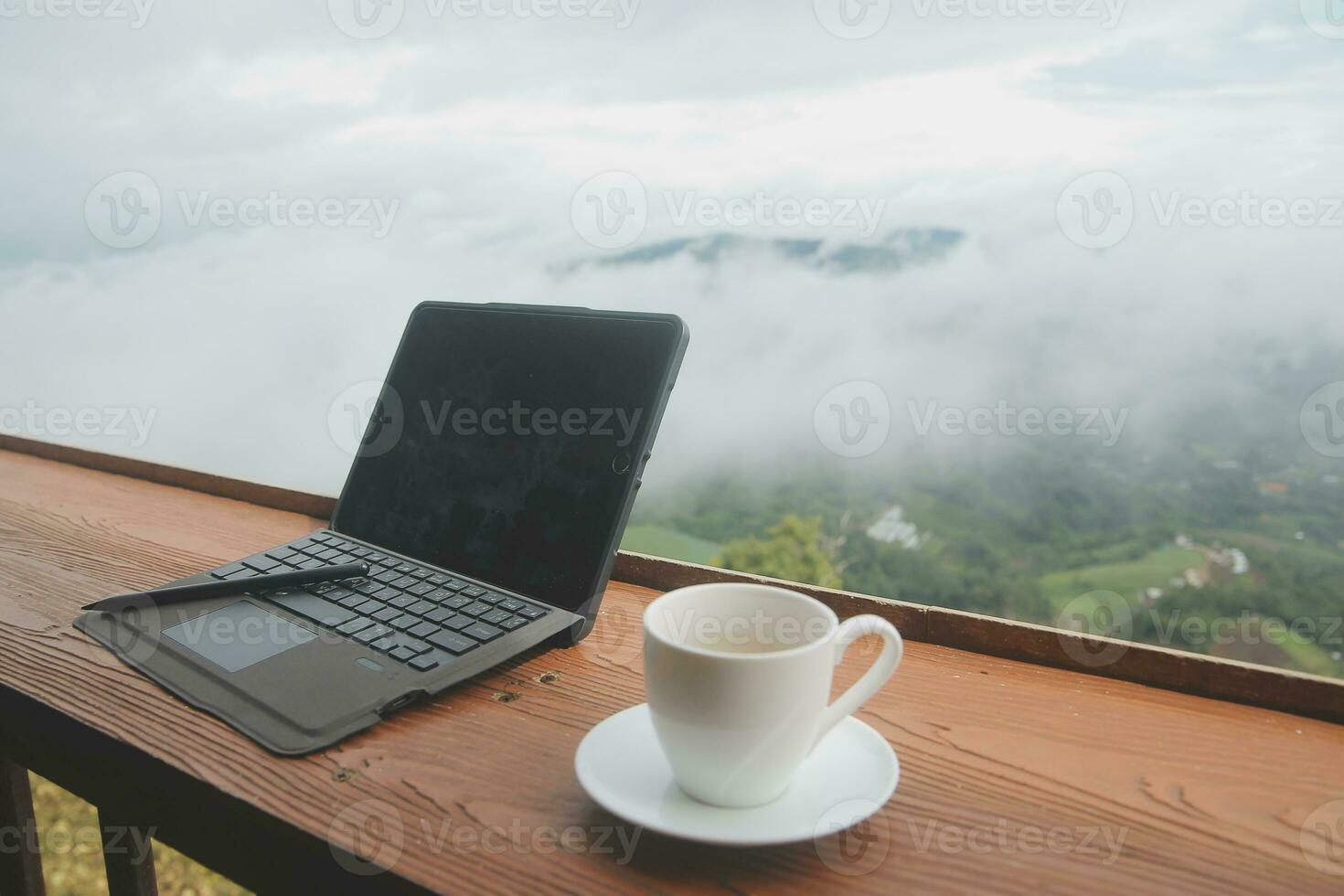 Computer Monitor, Keyboard, coffee cup and Mouse with Blank is on the work table at the sky mountain river and trees front view background. photo