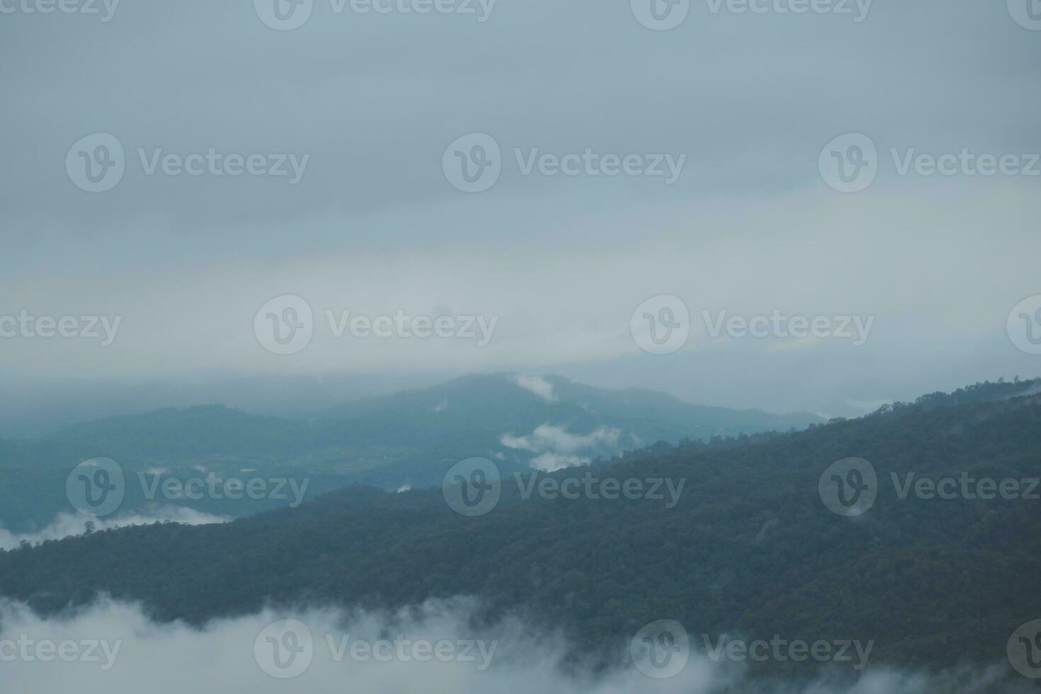Mountain range with visible silhouettes through the morning blue fog. photo