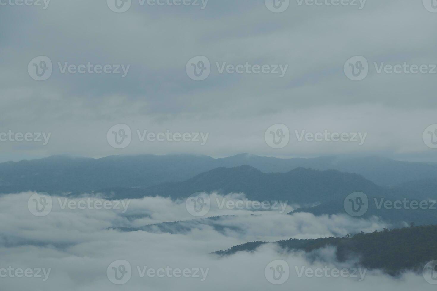 Mountain range with visible silhouettes through the morning blue fog. photo