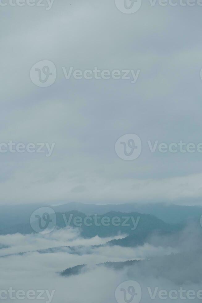 Mountain range with visible silhouettes through the morning blue fog. photo