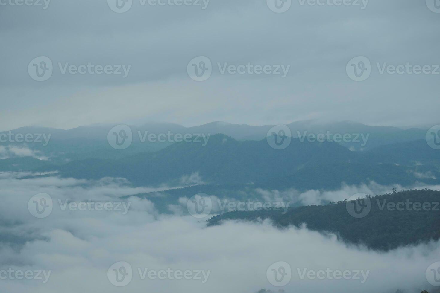 Mountain range with visible silhouettes through the morning blue fog. photo