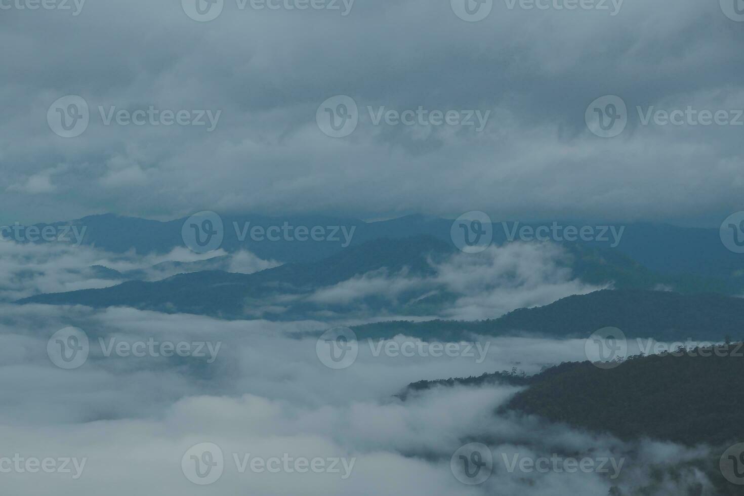 Mountain range with visible silhouettes through the morning blue fog. photo