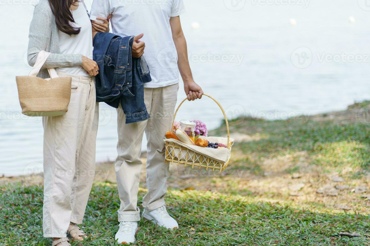 Pareja caminando en jardín con picnic cesta. en amor Pareja es disfrutando picnic hora en parque al aire libre foto