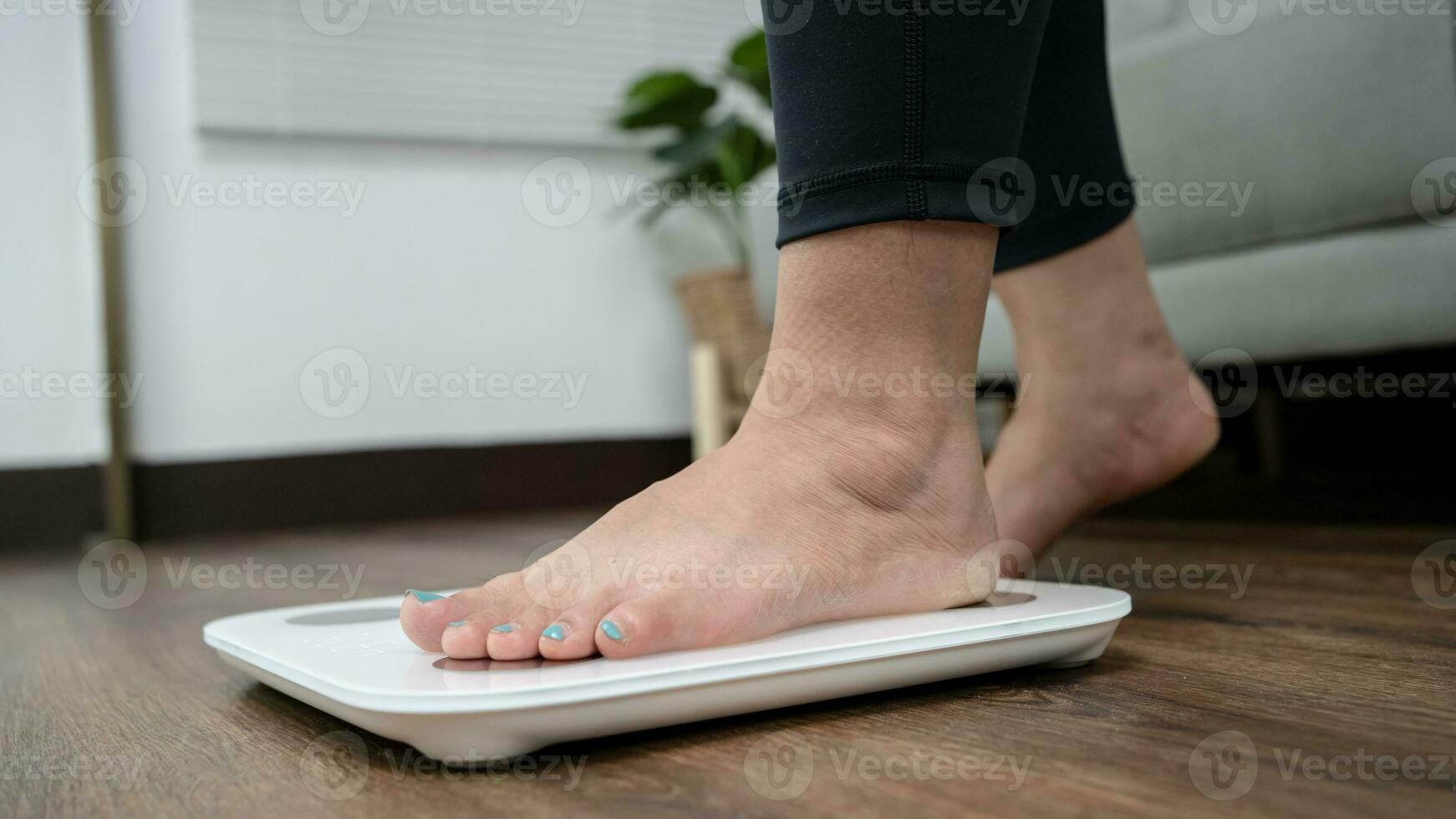 Fat diet and scale feet standing on electronic scales for weight control. Measurement instrument in kilogram for a diet control. photo