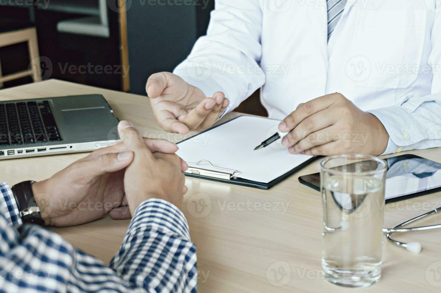 médico cuidado de la salud. profesional médico médico en blanco uniforme vestido Saco entrevista consultante paciente tranquilizador su masculino paciente Ayudar mano foto