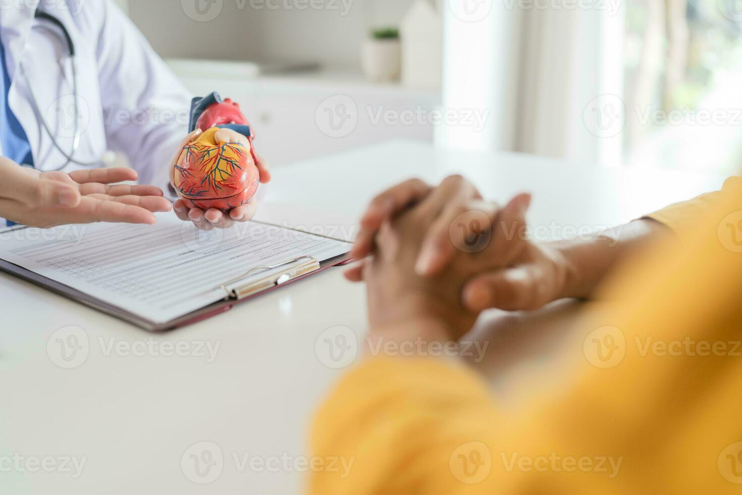 cardiología consulta tratamiento de corazón enfermedad. médico cardiólogo mientras consulta demostración anatómico modelo de humano corazón con Envejecido paciente hablando acerca de corazón enfermedades. foto