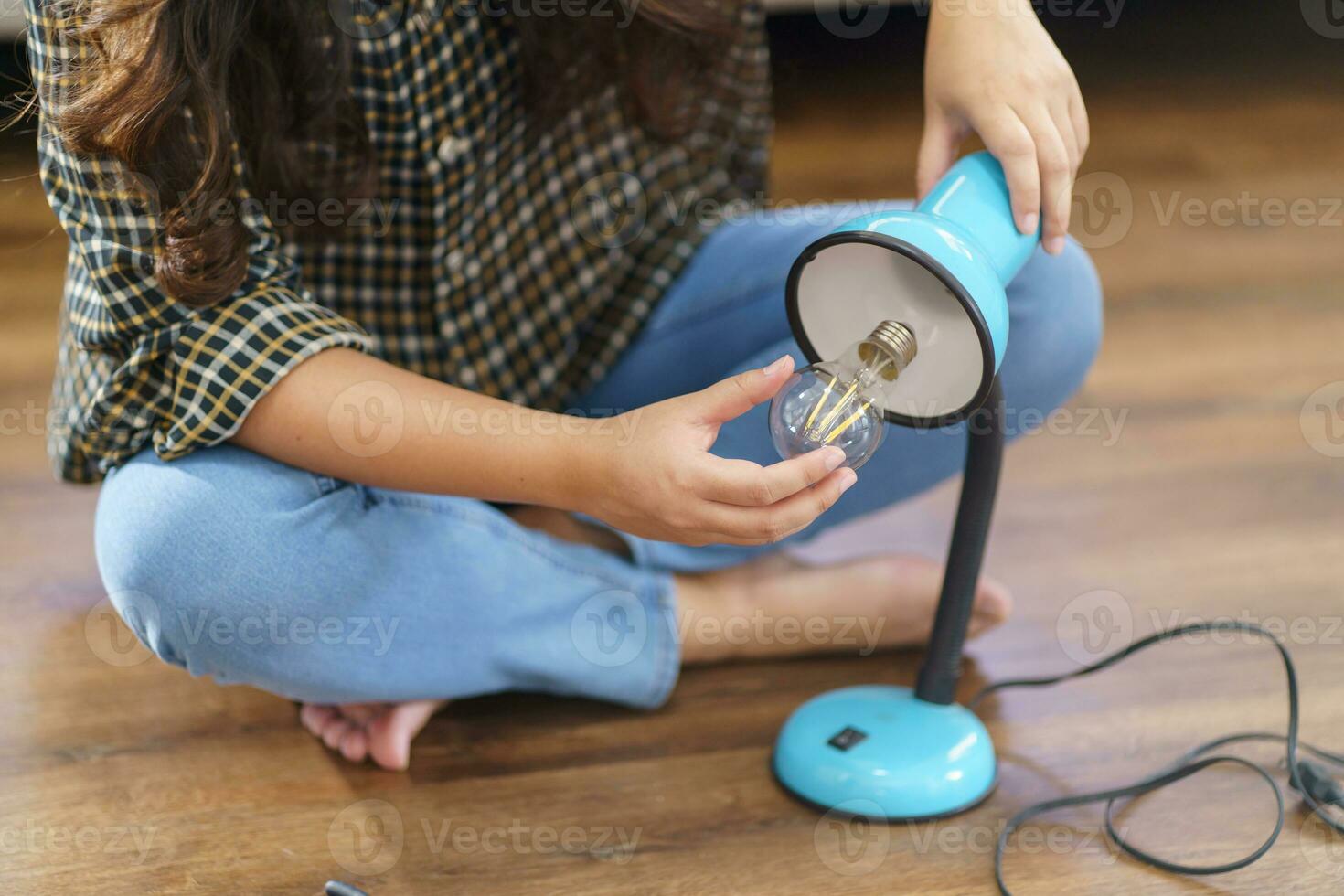 Asian Woman changing light bulb in lamp renovation using equipment to diy repairing light bulb and lamp sitting on the floor at home photo