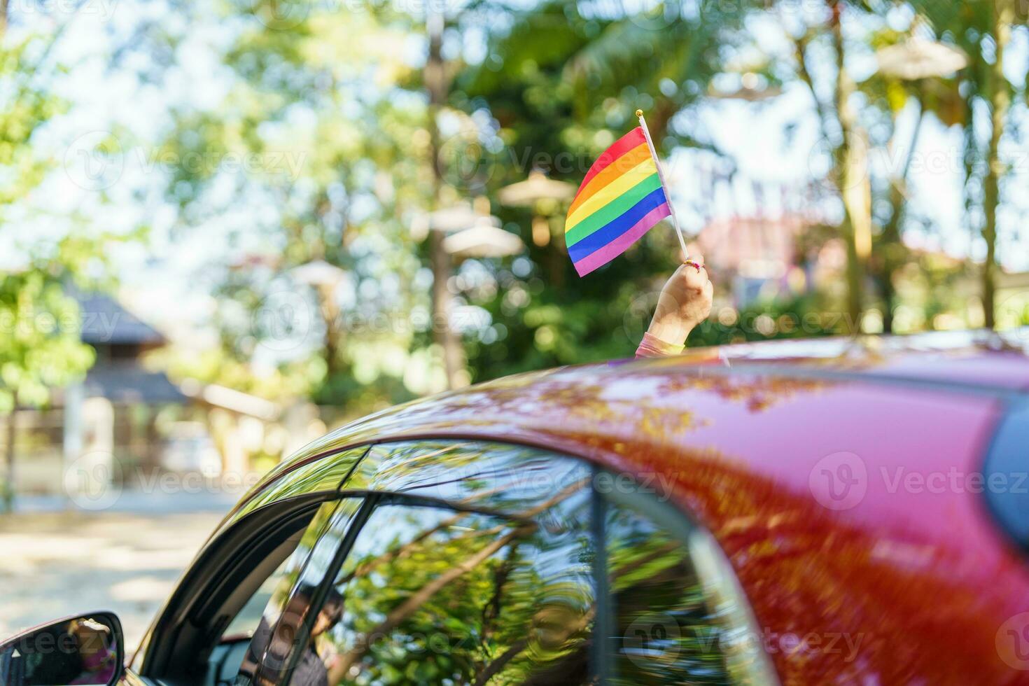 Happy Asian woman support LGBT pride parade in car. with Rainbow of LGBTQ or LGBTQIA. photo