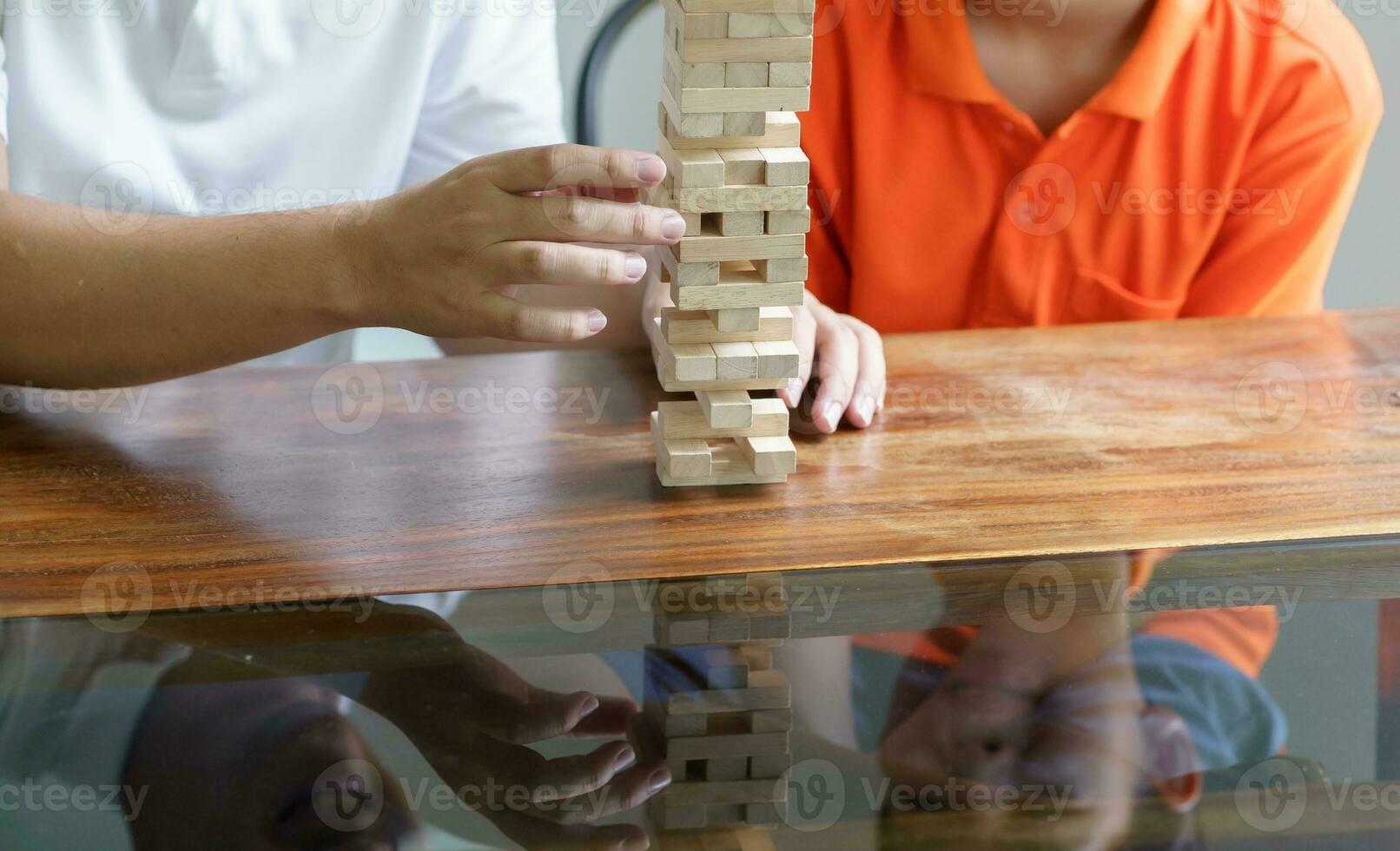 Asian father and son playing wood blocks game Carefree kid playing wood blocks game building constructor from blocks with father at home photo