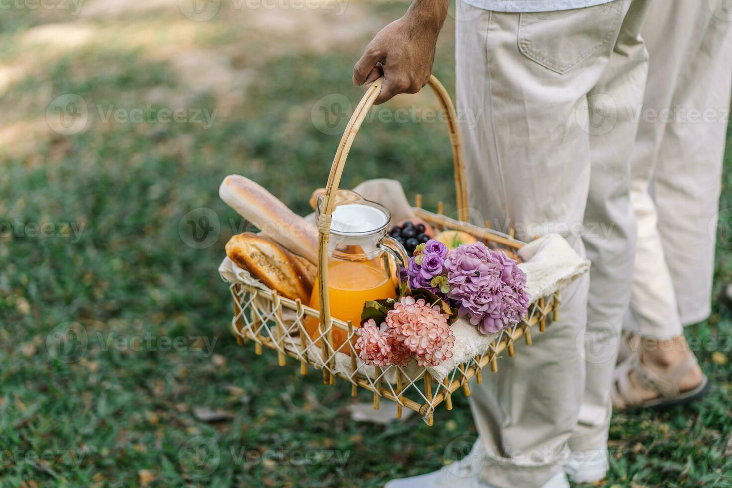 Pareja caminando en jardín con picnic cesta. en amor Pareja es disfrutando picnic hora en parque al aire libre foto