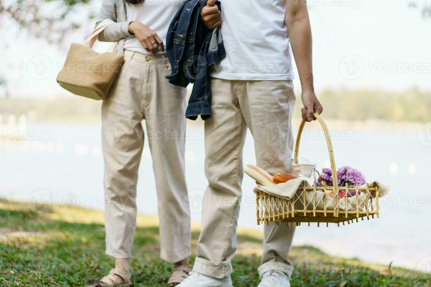 Pareja caminando en jardín con picnic cesta. en amor Pareja es disfrutando picnic hora en parque al aire libre foto