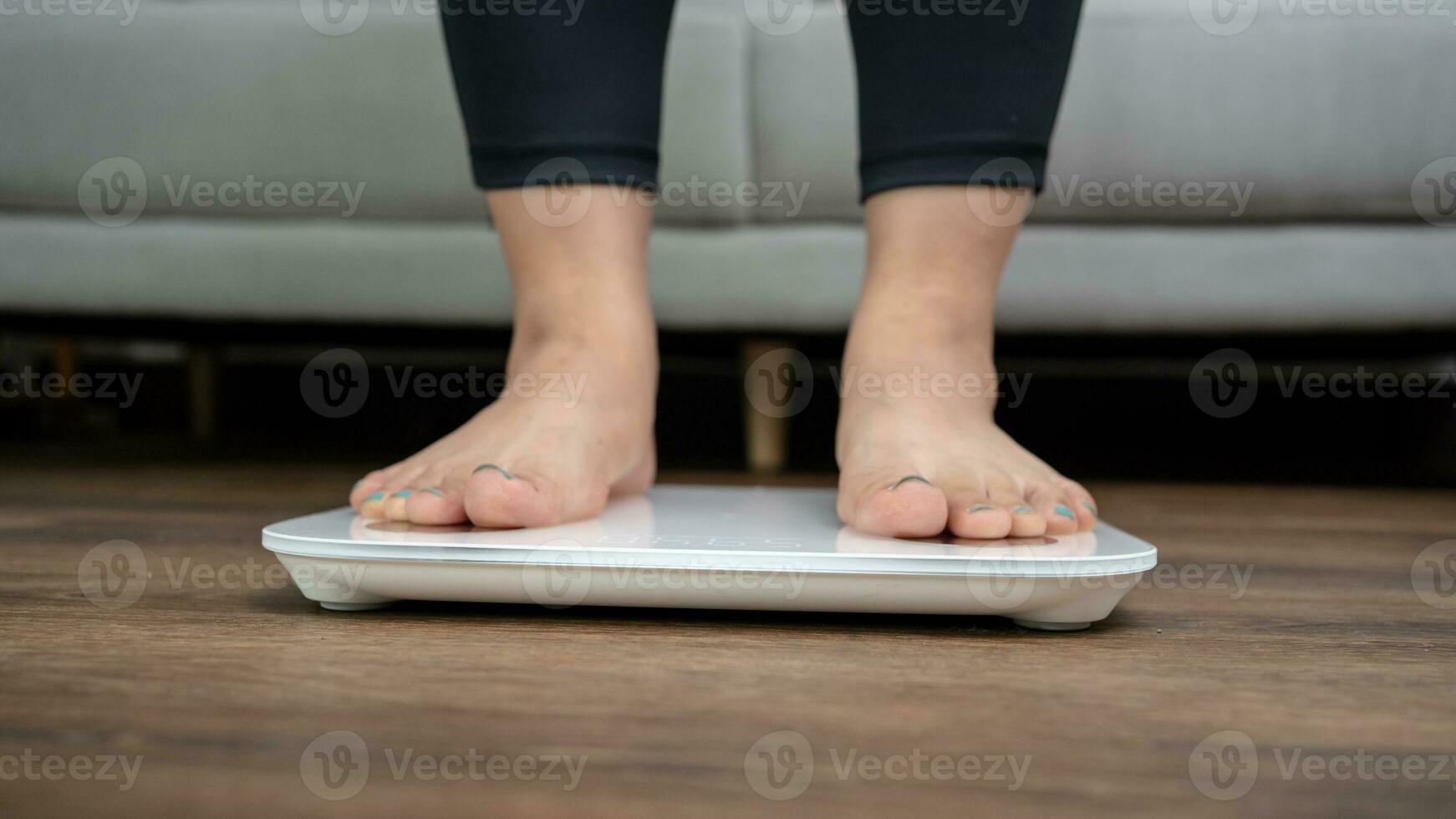 Fat diet and scale feet standing on electronic scales for weight control. Measurement instrument in kilogram for a diet control. photo