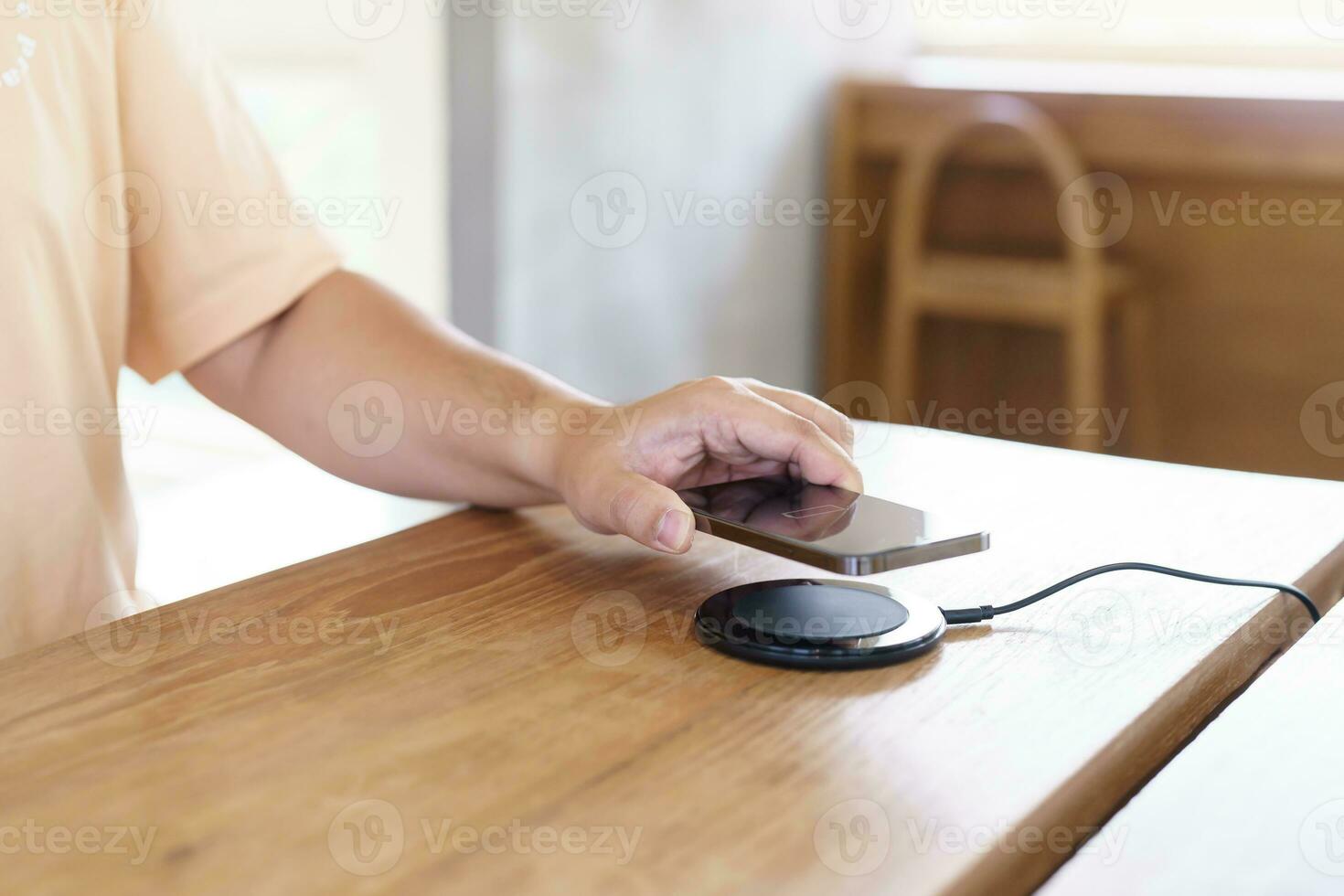 Charging mobile phone battery with wireless charging device in the table. Smartphone charging on a charging pad. Mobile phone near wireless charger Modern lifestyle technology concept. photo