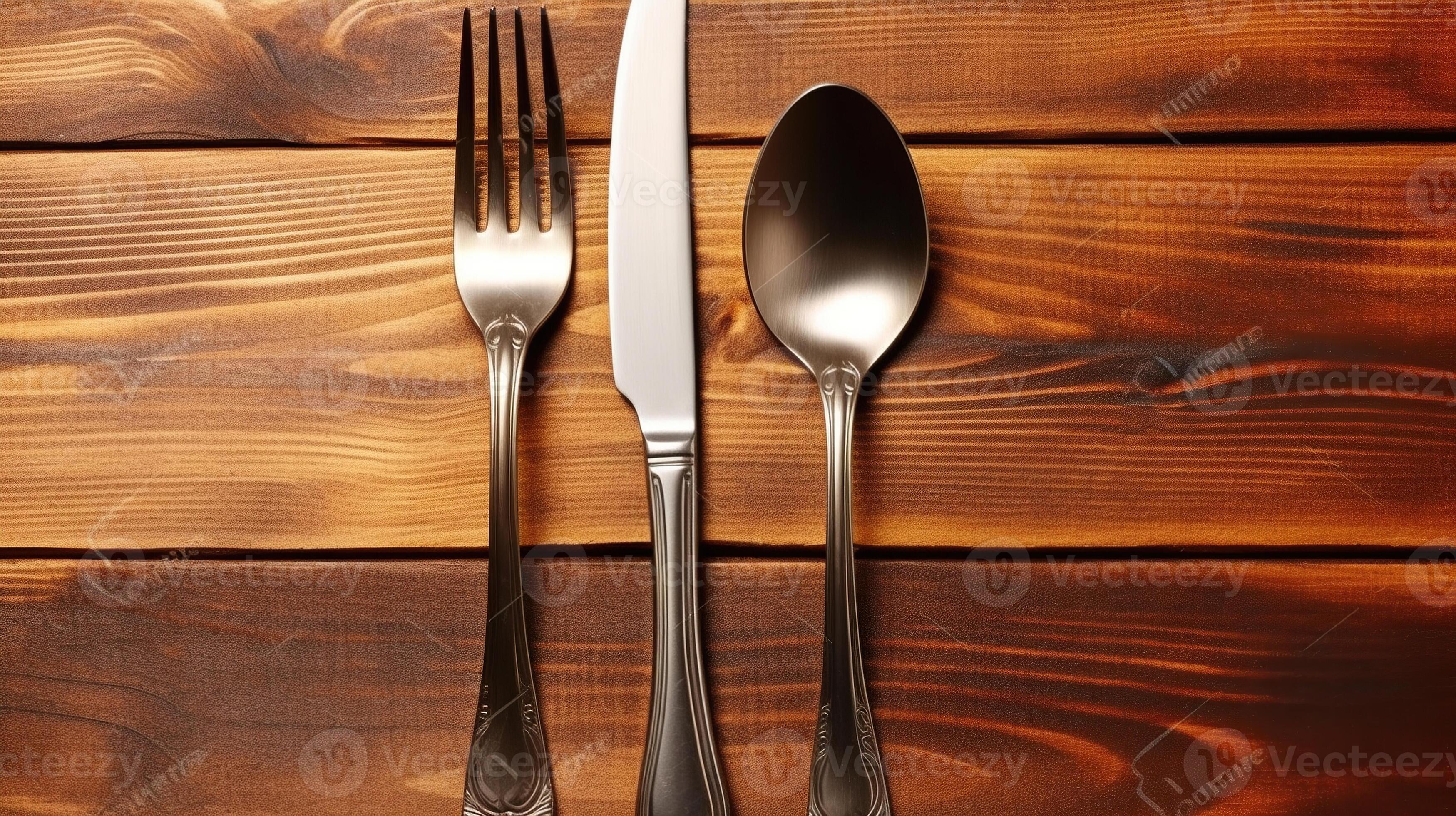 Vintage silver knife and fork on brown wooden textured table. Classic