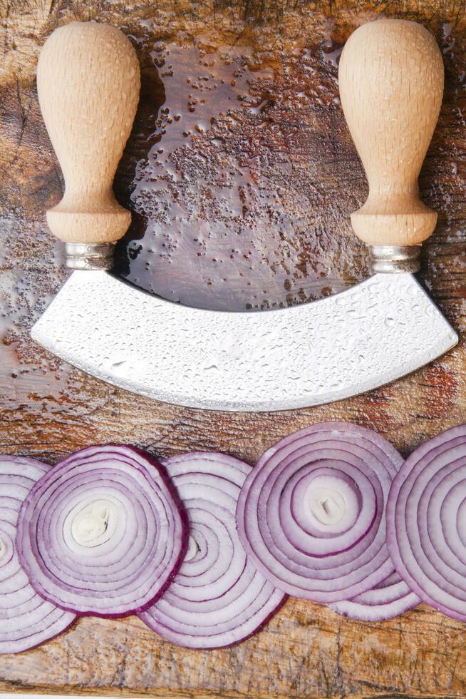 a knife and a bunch of onions on a cutting board photo