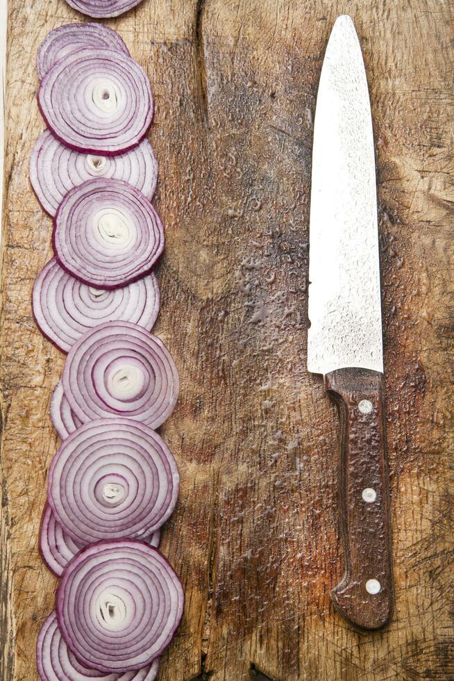 a knife and a bunch of onions on a cutting board photo