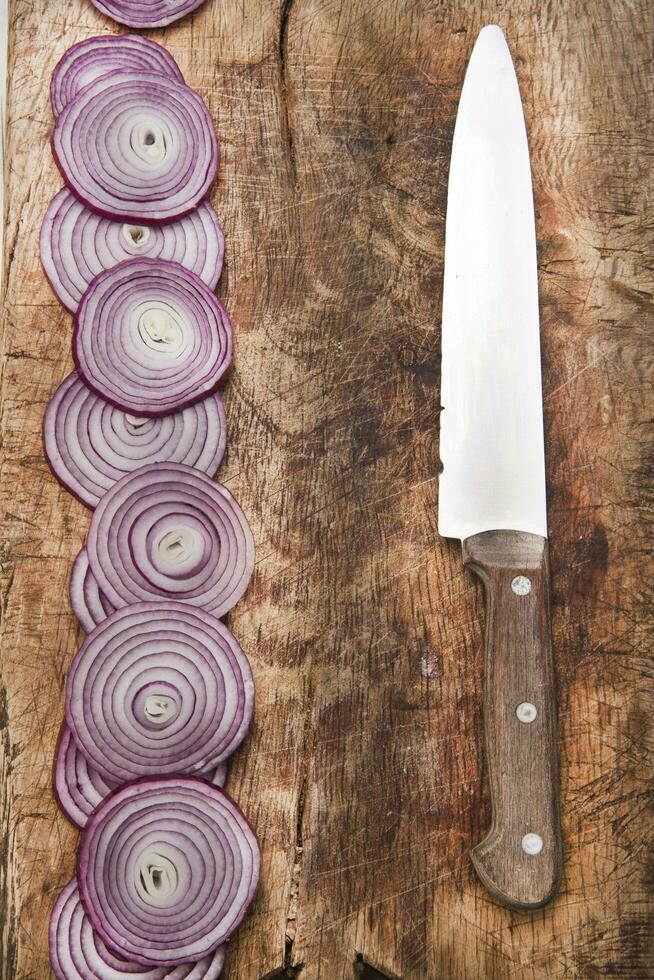 a knife and a bunch of onions on a cutting board photo