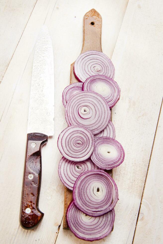 un cuchillo y un manojo de cebollas en un corte tablero foto