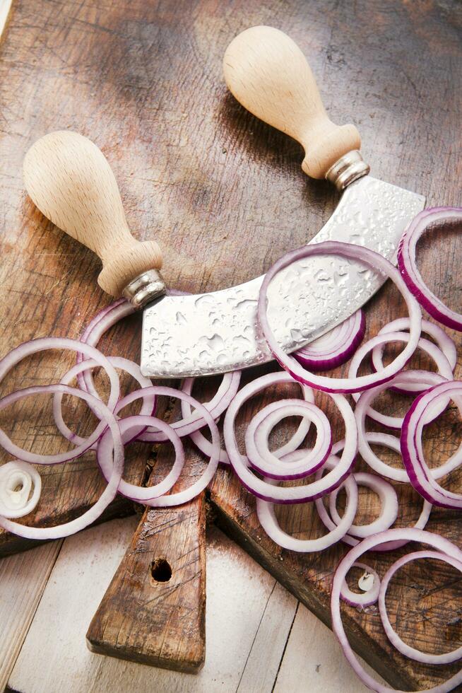 a knife and a bunch of onions on a cutting board photo