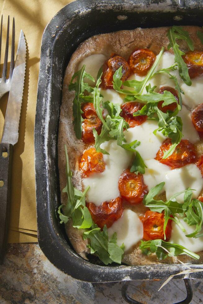 pizza con tomate y rúcula foto