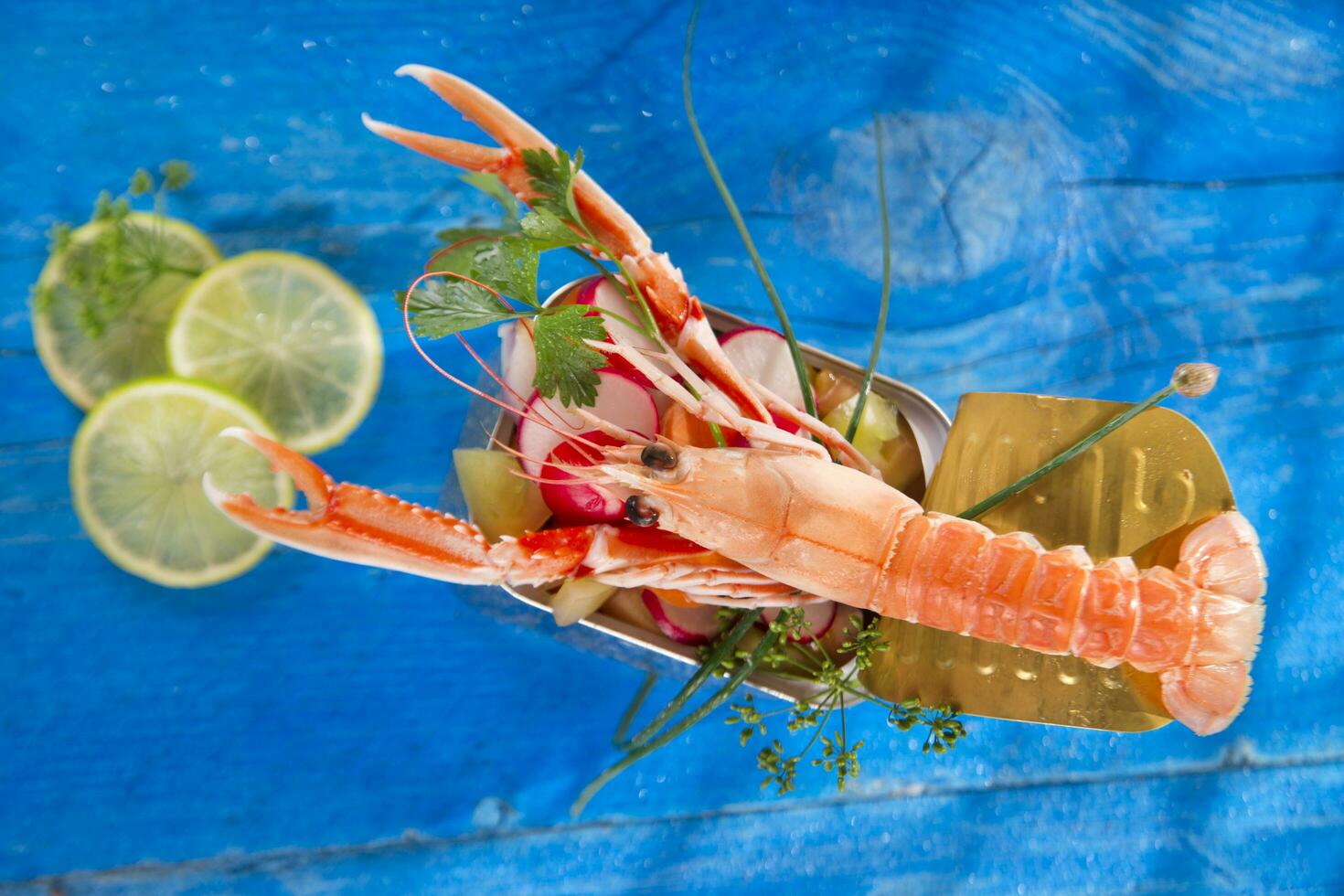 a shrimp in a container with a lime on a blue table photo