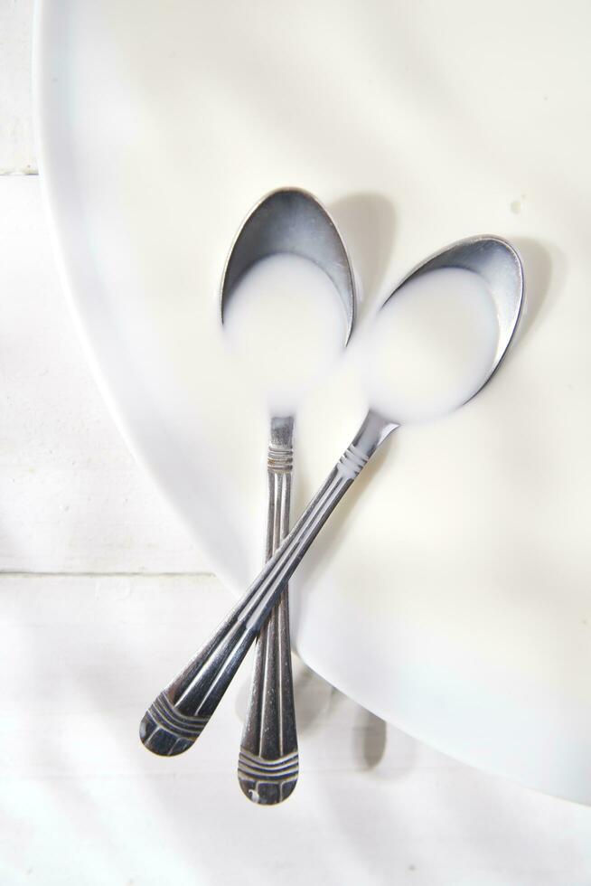 two spoons on a white plate with milk photo