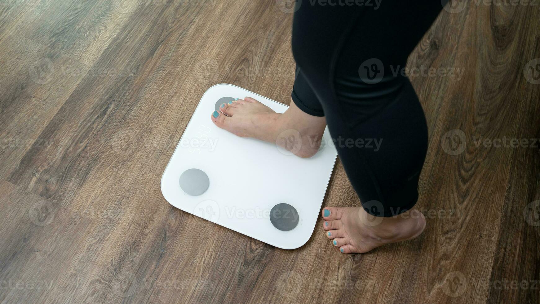 feet standing on electronic scales for weight control. Measurement instrument in kilogram for a diet control photo