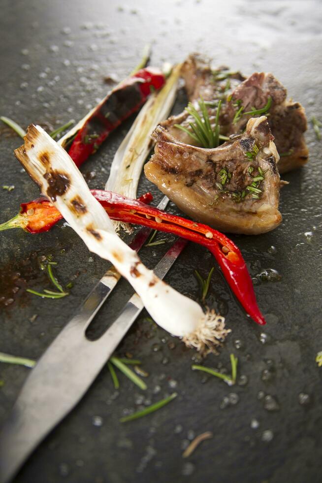 grilled lamb chops with herbs and spices on a black slate photo