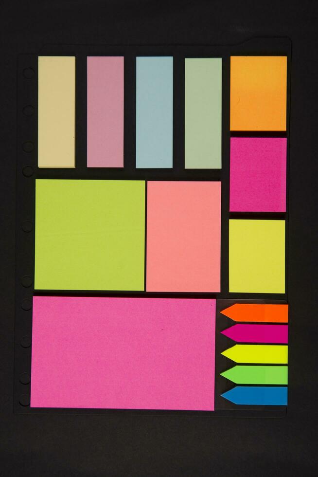 many colorful sticky notes are arranged on a black surface photo