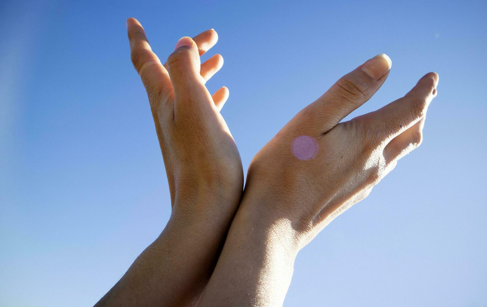 Female hands in the blue sky in the backlight photo