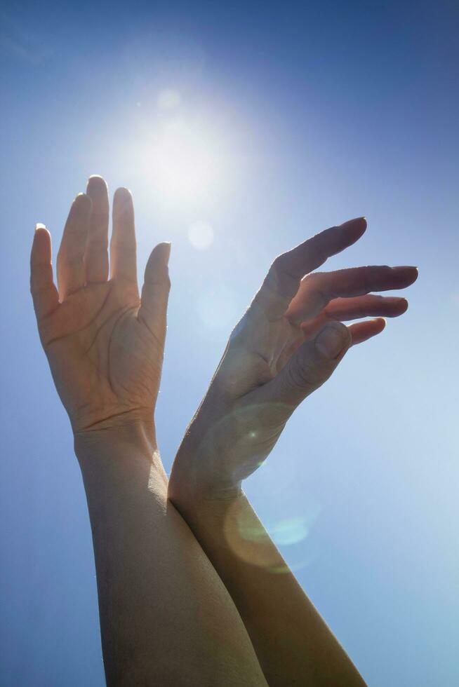 Female hands in the blue sky in the backlight photo