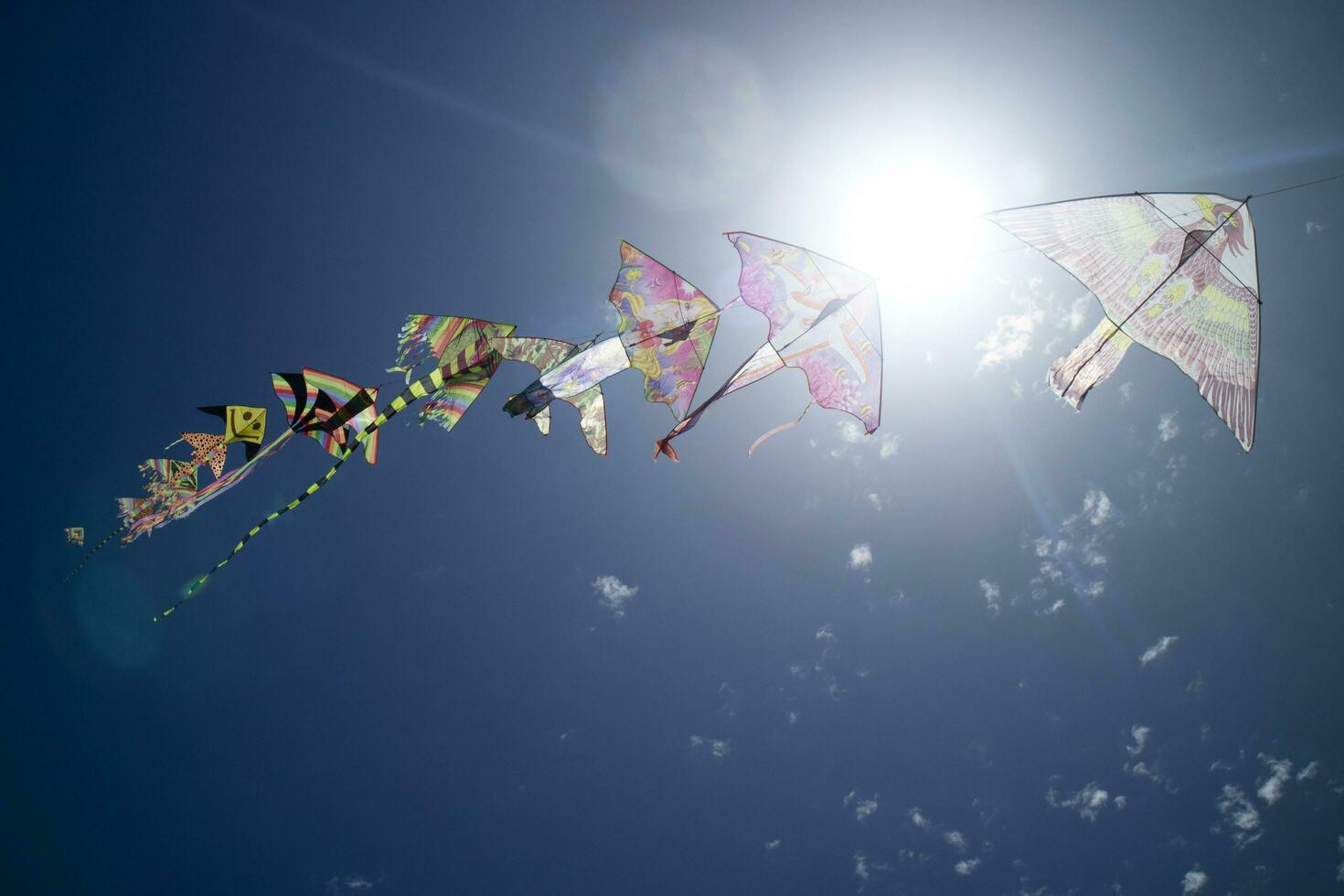 Series of colorful kites flying in the blue sky photo