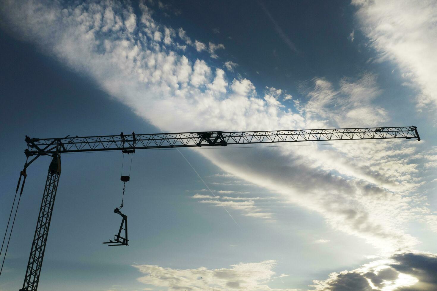 el perfil de un construcción grua a puesta de sol foto