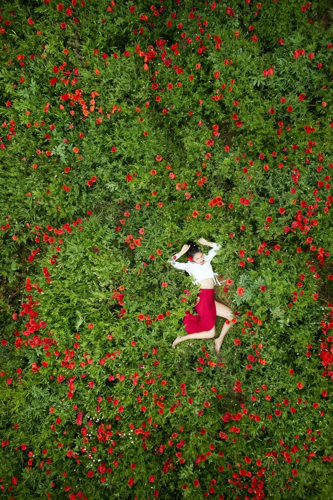 Aerial shot of a girl lying in a poppy field photo
