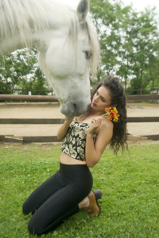 Beautiful girl affectionately stroking a white horse photo