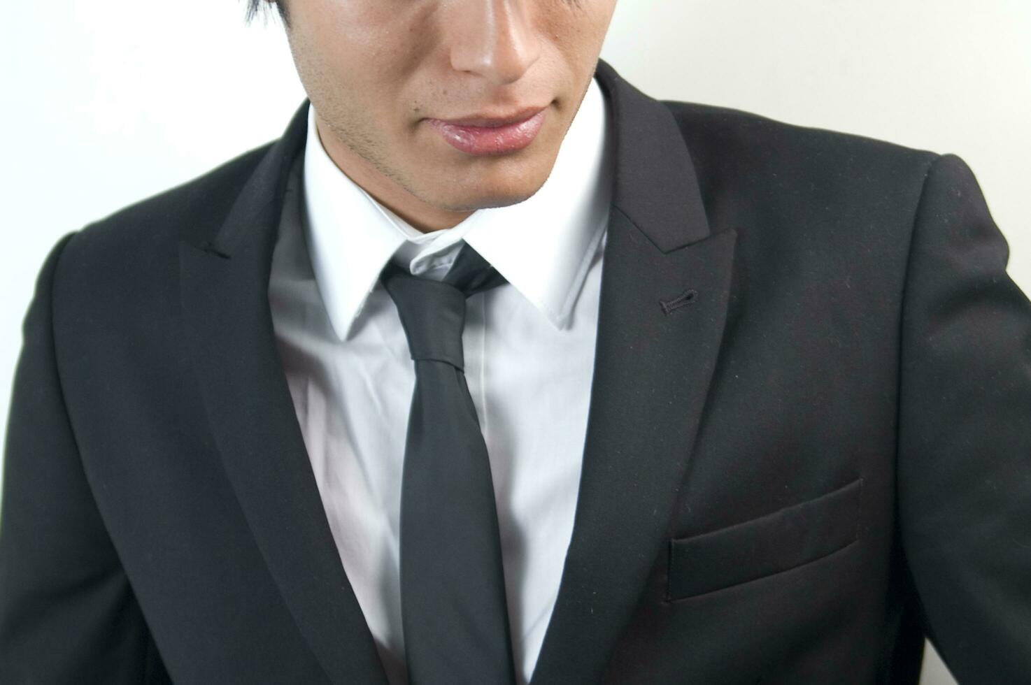 a man in a black suit and tie looking down photo