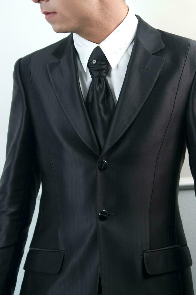 a man in a suit and tie standing against a wall photo