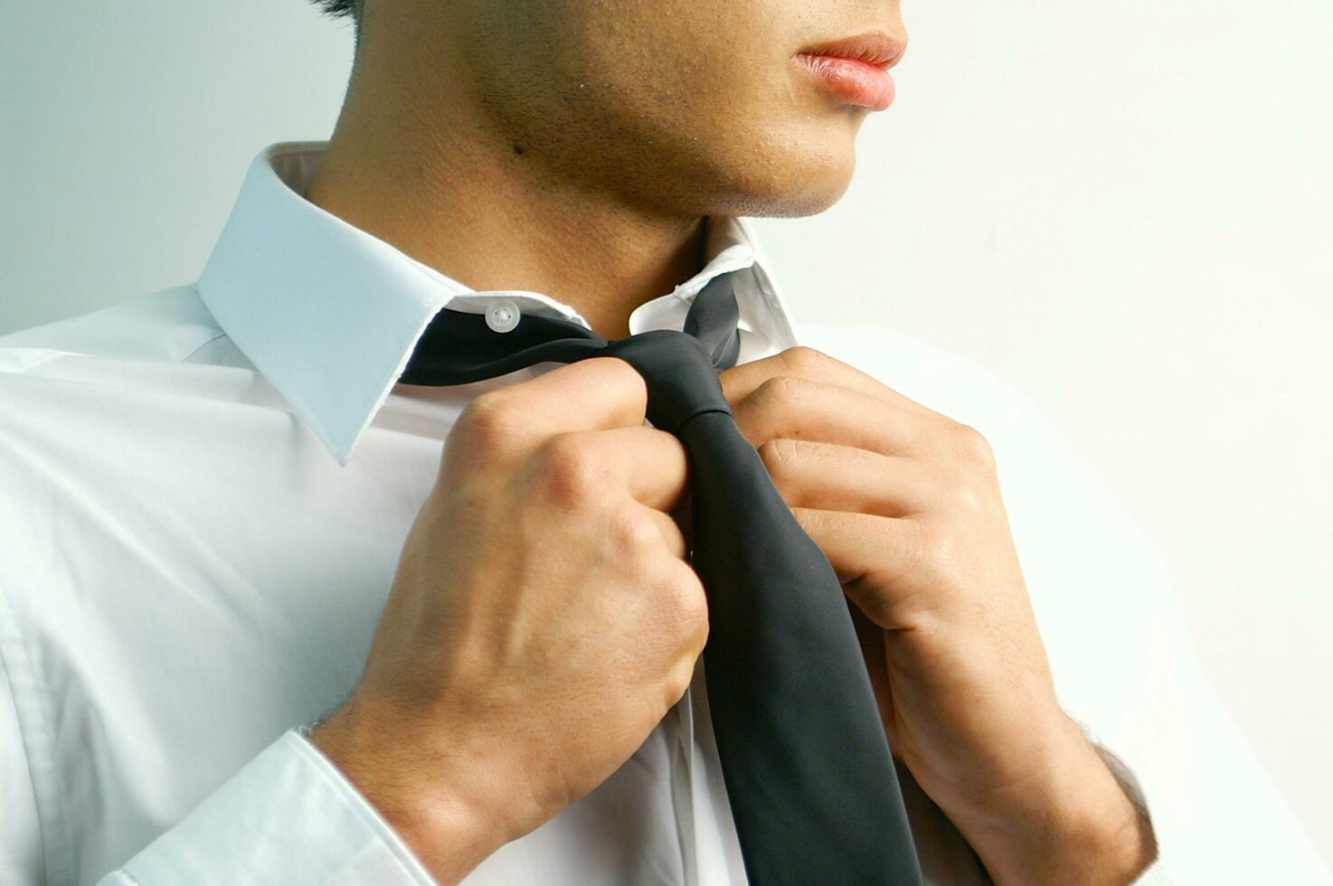 a man in a suit and tie standing against a wall photo