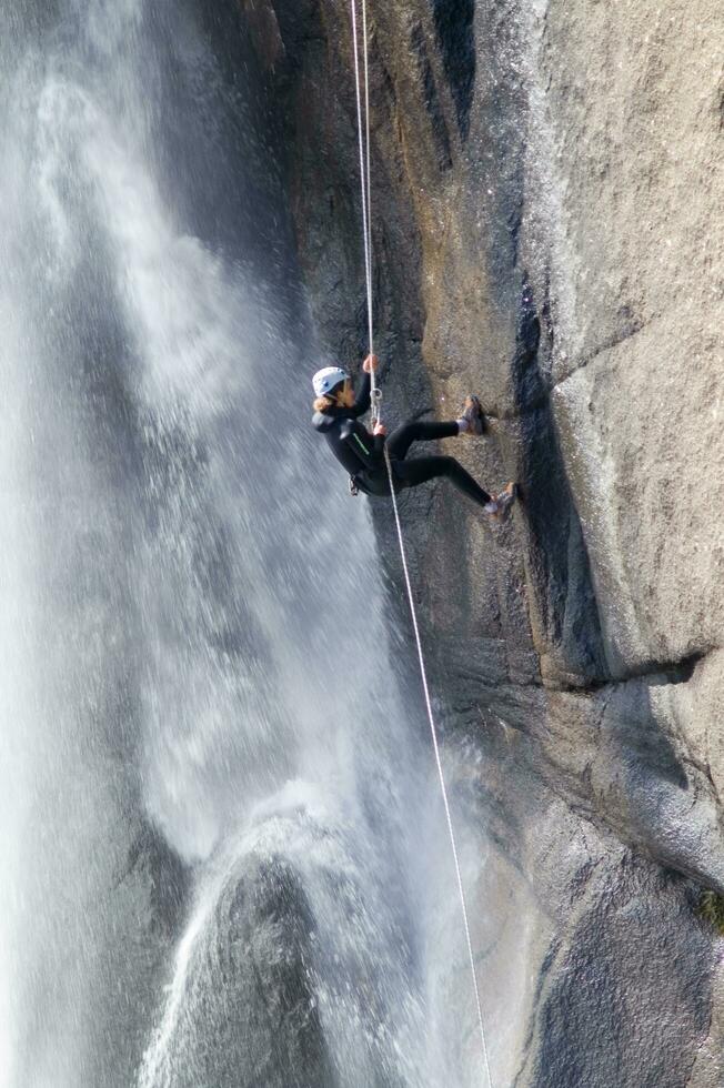 un persona en un cuerda alpinismo arriba un cascada foto