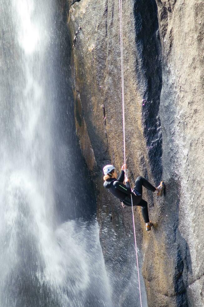 a person on a rope climbing up a waterfall photo