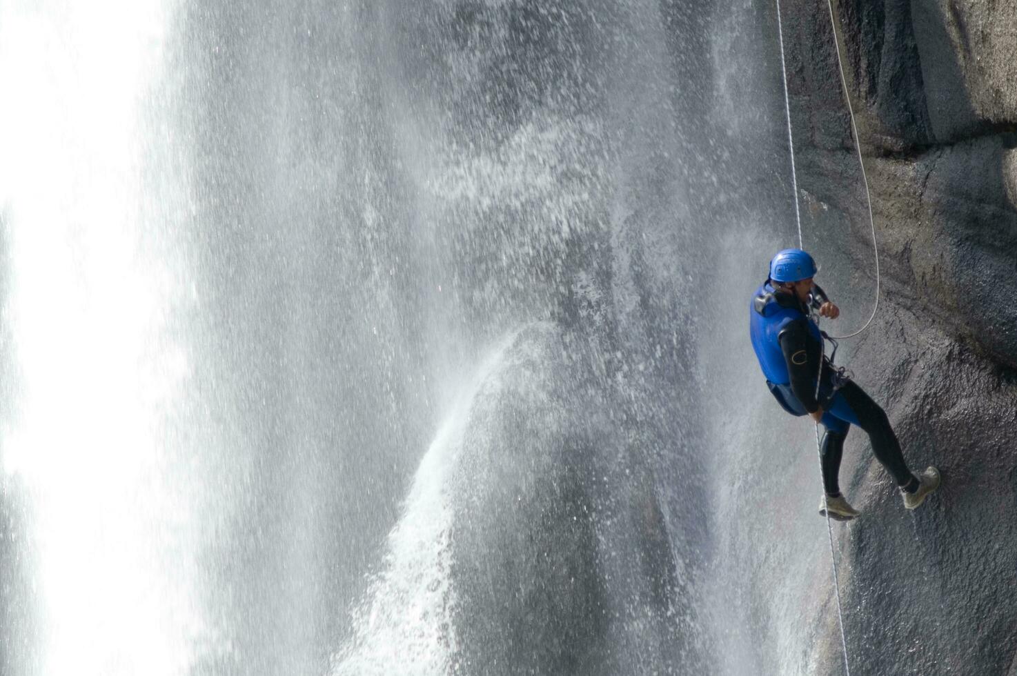 a person on a rope climbing up a waterfall photo