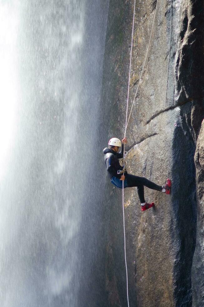 a person on a rope climbing up a waterfall photo