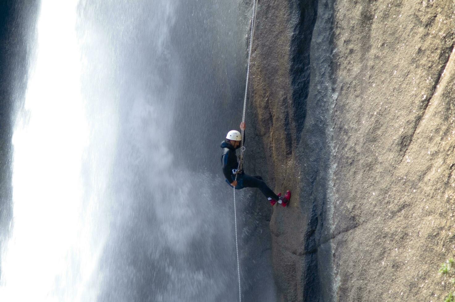 a person on a rope climbing up a waterfall photo